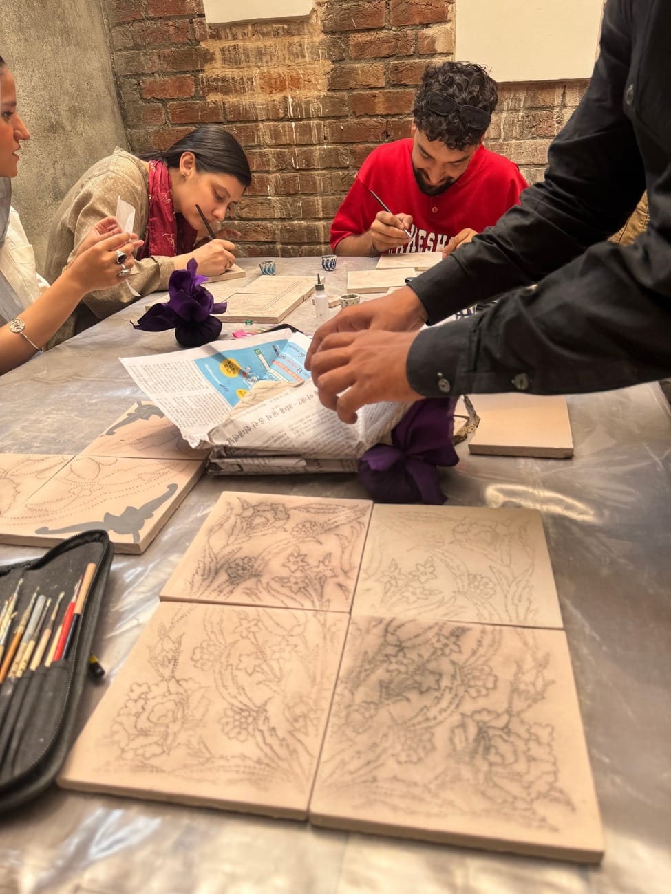 Transferring traditional motifs onto tiles during a Kashi Kari session.