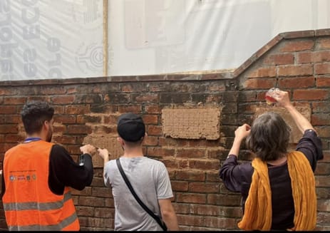 Hands-on lime plaster practice on a historic brick wall.