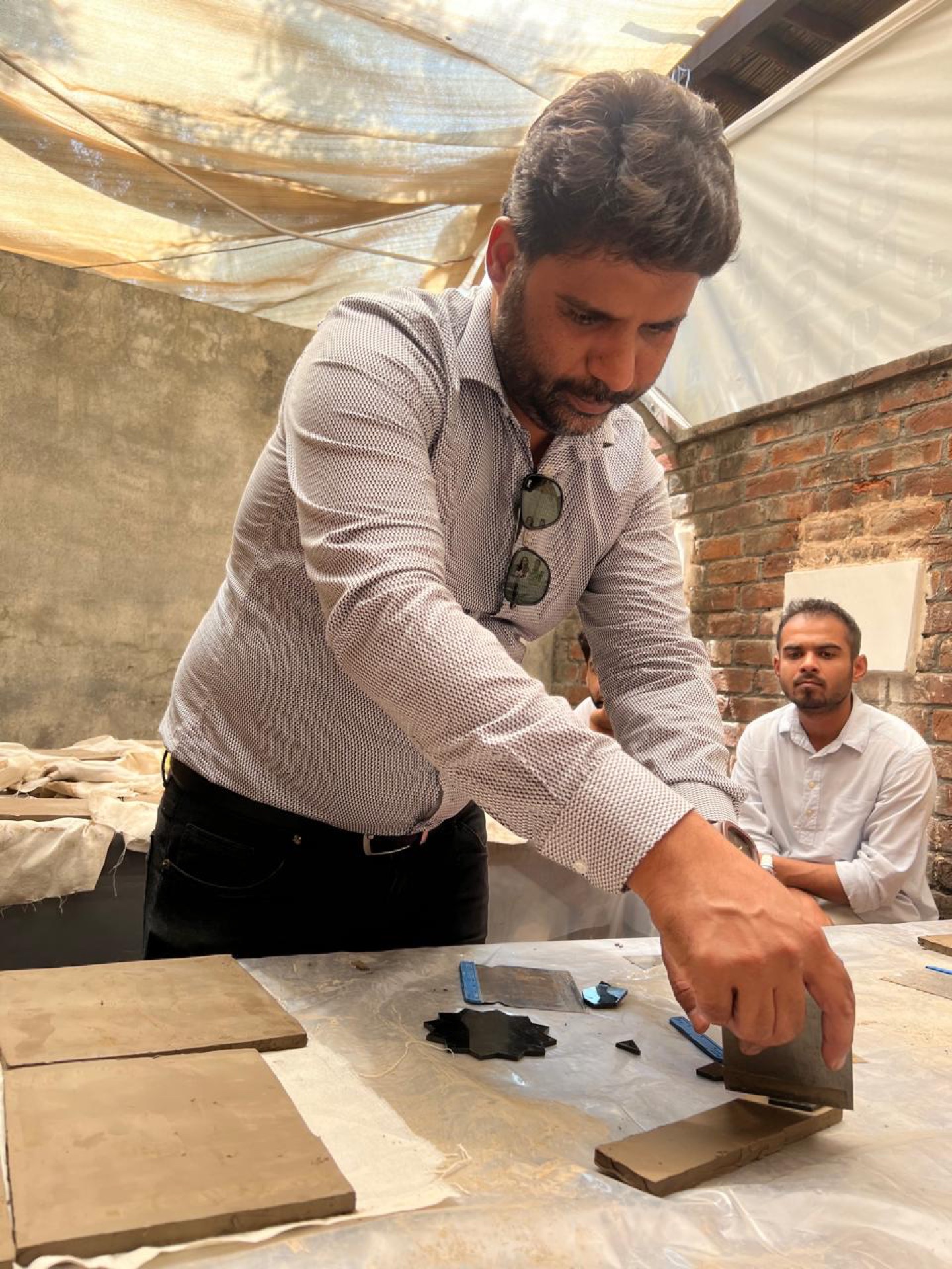 Kashi Kari hands-on practice with Kashi Kari Experts Amjad Daudpota, Taimoor Daudpota and Arsalan Daudpota — brush painting traditional Sozenkari patterns on tiles.